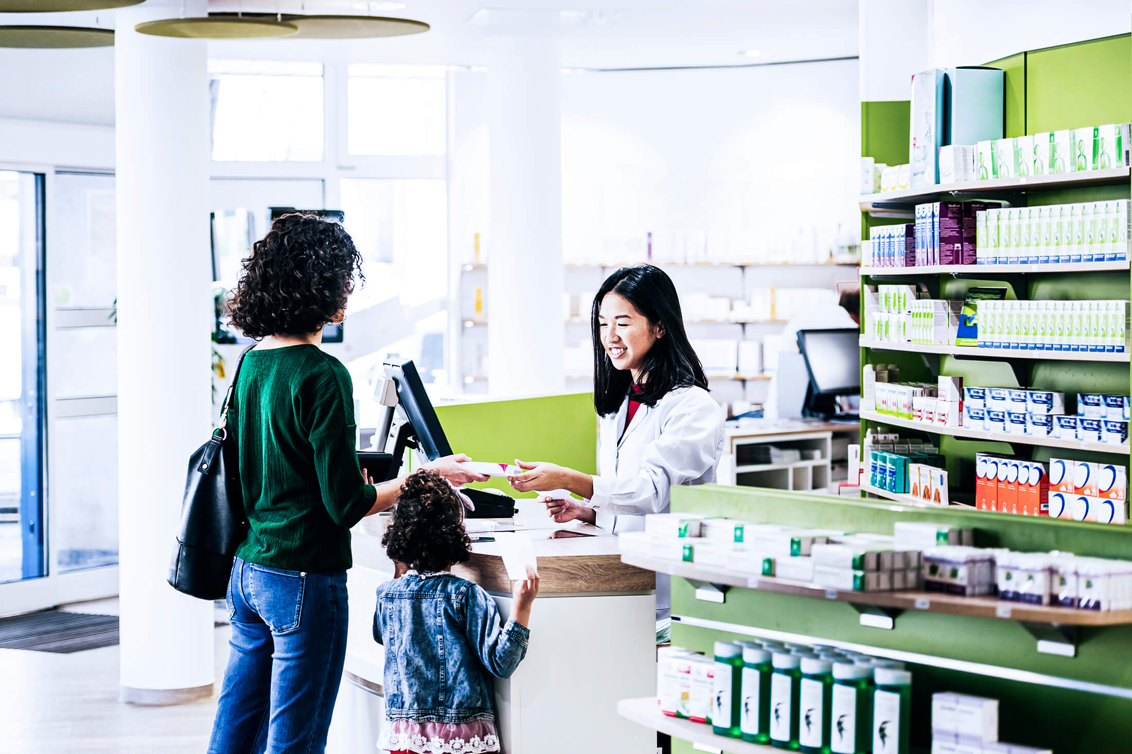 Como aumentar as vendas na farmácia? Na imagem, uma farmacêutica atendendo uma mãe e sua filha.